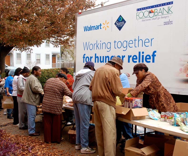 Walmart associates help serve food outside Walmart mobile hunger relief truck.