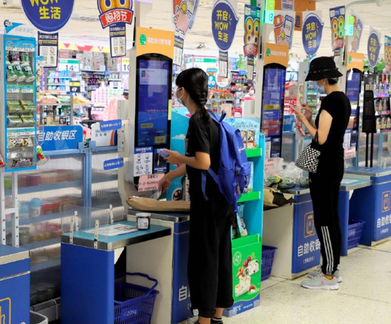 International Walmart customers use self-checkout systems.