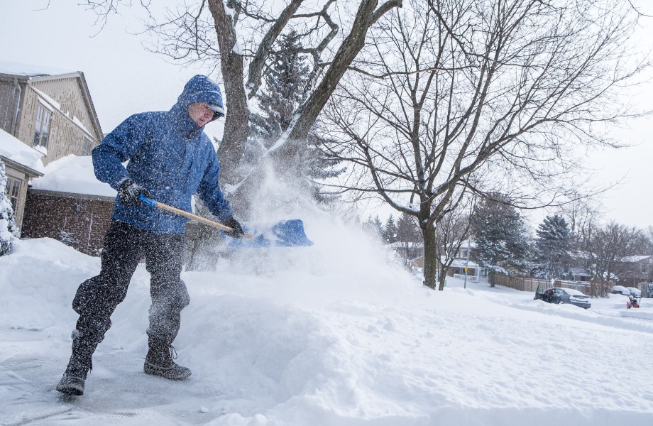 A man removes snow with a shovel